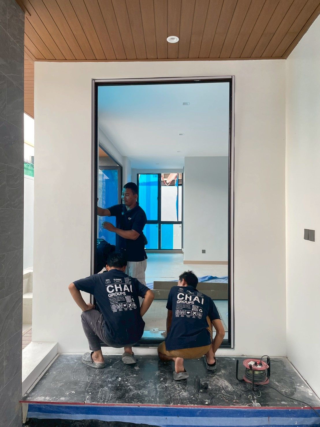 ทีมช่างของ Chaibuilder Groups ระหว่างติดตั้งประตูทางเข้าอลูมิเนียม TOSTEM